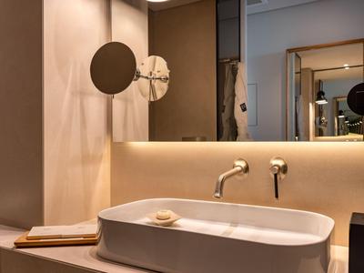 Nowoczesna umywalka łazienkowa z podświetlanym lustrem i okrągłymi lustrami powiększającymi.