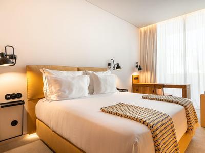 Nowocześnie urządzony pokój hotelowy z podwójnym łóżkiem, stolikami nocnymi i biurkiem przy oknie