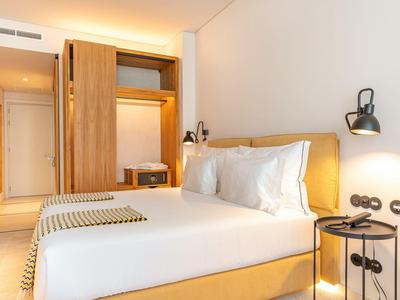 Nowocześnie urządzony pokój hotelowy z łóżkiem podwójnym i drewnianą szafą.