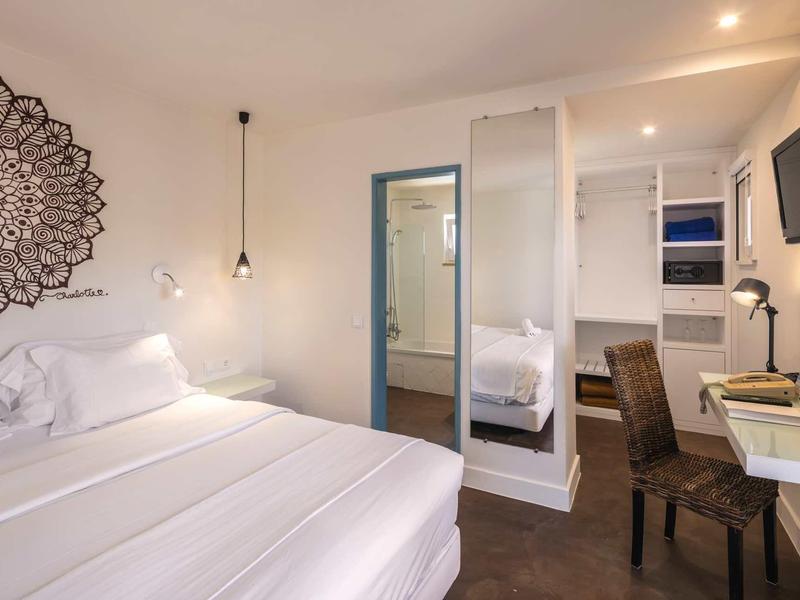 Modern hotelkamer met tweepersoonsbed, grote spiegel en bureau.