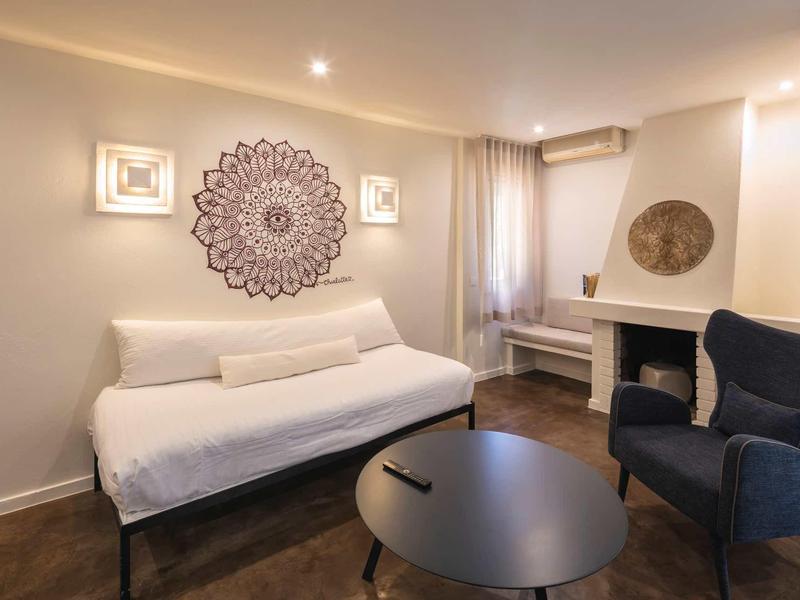 Modern ingericht hotelkamer met bank, open haard en decoratieve wandkunst.