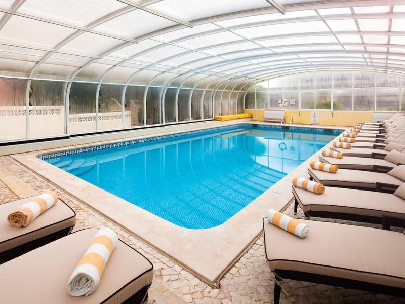 Overdekt zwembad met ligstoelen en handdoeken in een hotel.