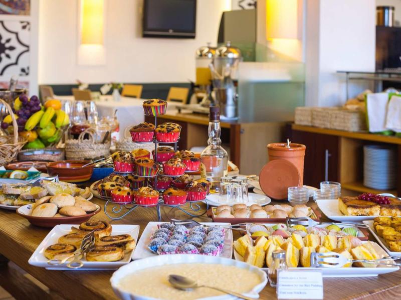 Buffet met diverse gebakjes, taarten en fruit in een lichte ruimte.