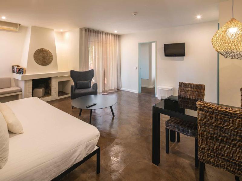 Modern ingerichte woonkamer met bank, eettafel, open haard en toegang tot een balkon.