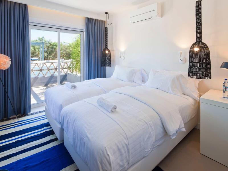 Lichte hotelkamer met twee eenpersoonsbedden en balkon met uitzicht op groen.