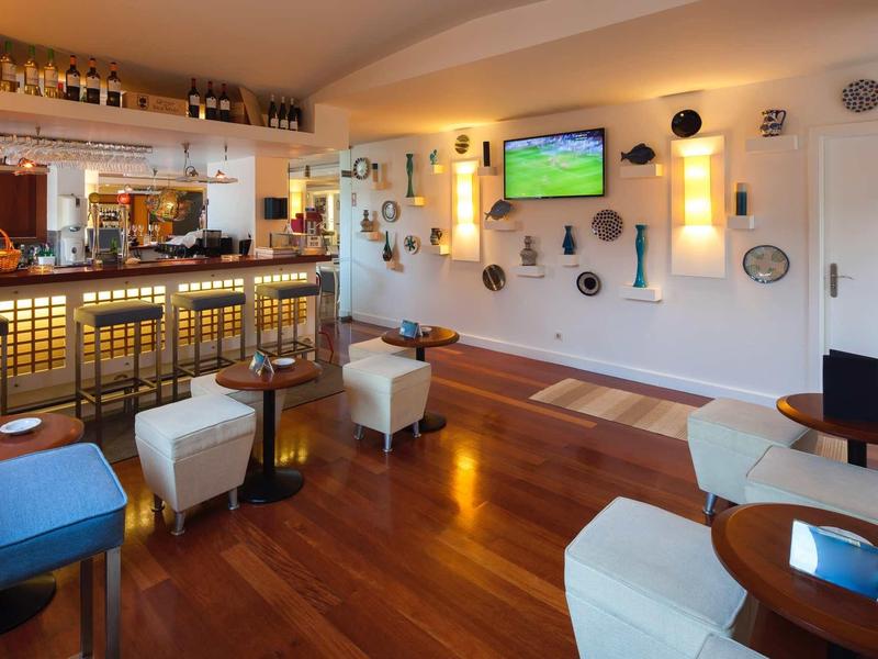 Gezellige hotelbar met houten vloer, krukken en een tv aan de muur