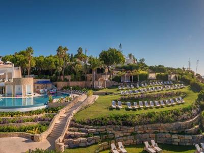 Panoramisch uitzicht op een luxe resort met meerdere zwembaden, terrastuinen en zeezicht.