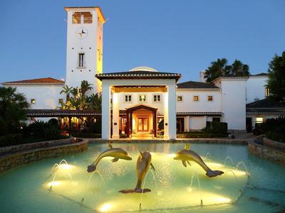 Verlichte hotel fontein met springende dolfijnbeelden en elegant gebouw op de achtergrond