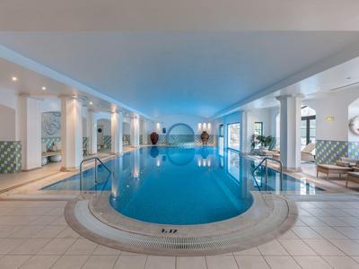 Binnenzwembad in een modern wellnesshotel met ronde ramen en ligstoelen.