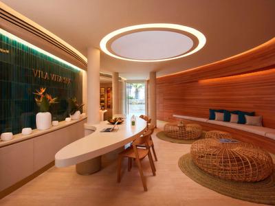 Moderne, gezellige receptieruimte met ovale tafel, houten panelen en ronde zitmeubels.