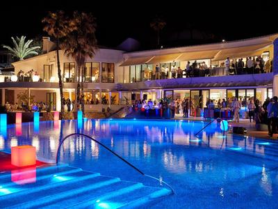 Verlicht hotelzwembad met gasten en kleurrijke lichten 's nachts