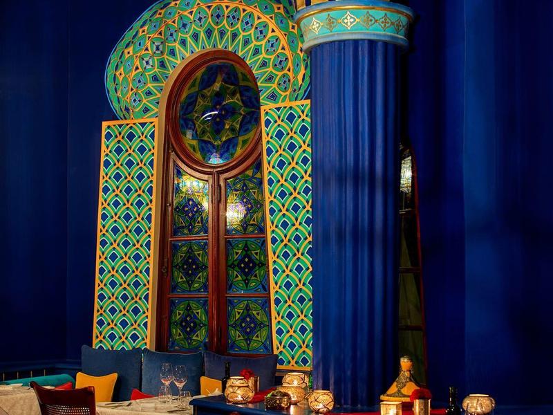 Luxe eetkamer met blauw-gouden decor en sierlijk raam in een hotel.