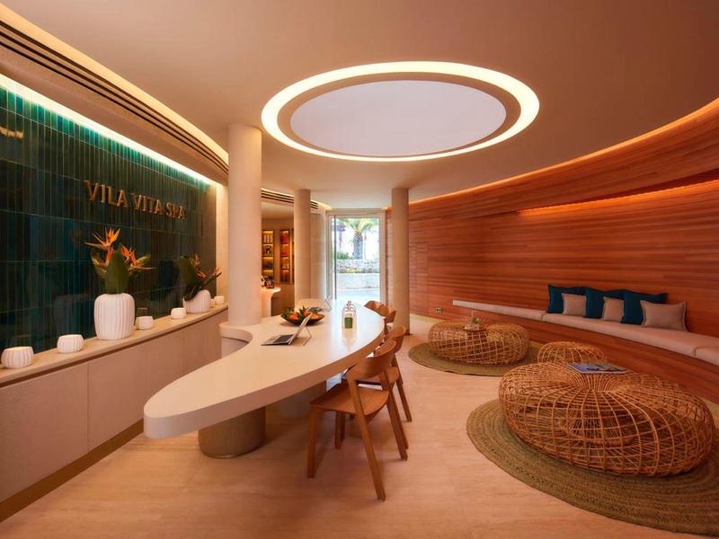 Moderne, gezellige receptieruimte met ovale tafel, houten panelen en ronde zitmeubels.