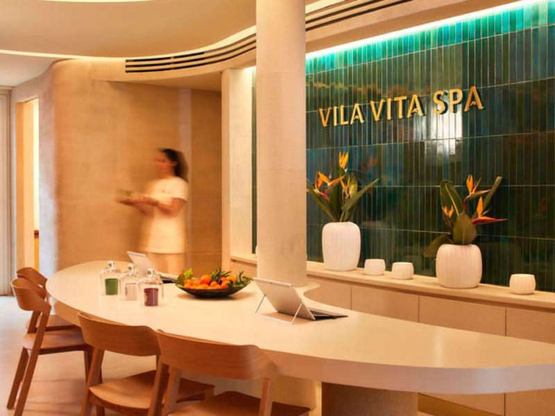 Moderne spa-receptie met gebogen balie en stijlvolle houten meubels in warm licht.