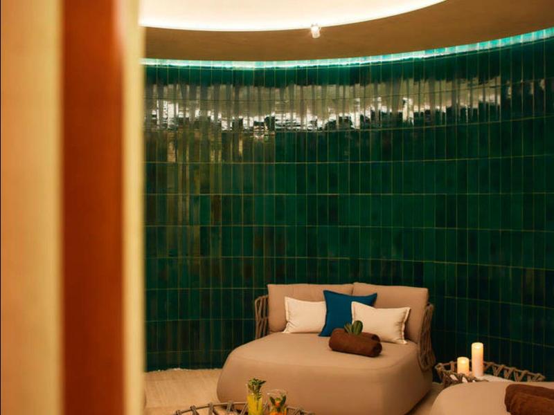 Gezellige lounge met beige fauteuils en groene tegels, zacht verlicht.