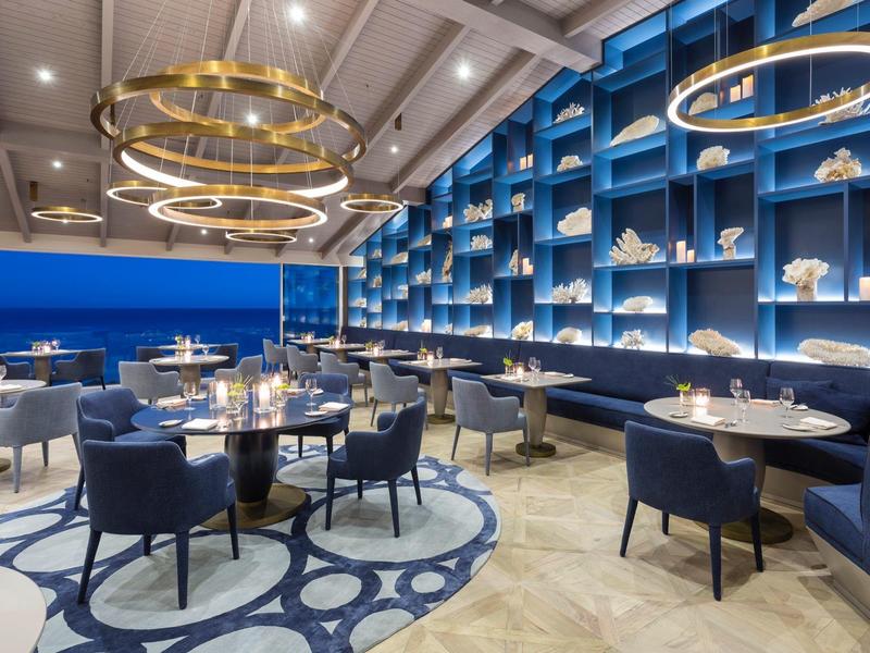 Elegant hotelrestaurant met blauwe muren, moderne gouden kroonluchters en stijlvolle zitgedeeltes.