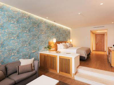 Modern eingerichtetes Hotelzimmer mit blau gemusterter Wand, Doppelbett und Sofa