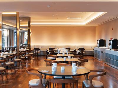 Elegancka sala jadalna hotelu z nowoczesnymi drewnianymi meblami i ciepłym oświetleniem.
