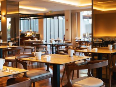 Jasno oświetlona sala jadalna hotelu z drewnianymi meblami i nakrytymi stołami.