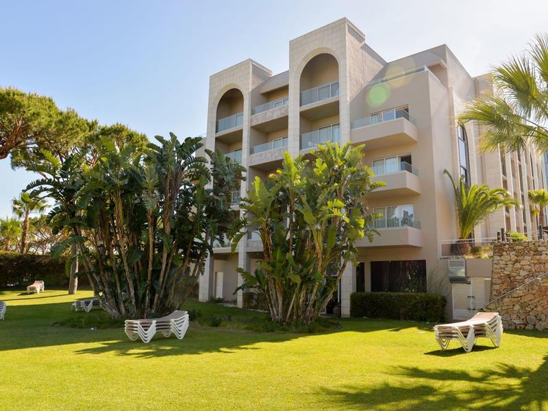 Hotelová budova s více patry a tropickou zahradou za slunečného počasí