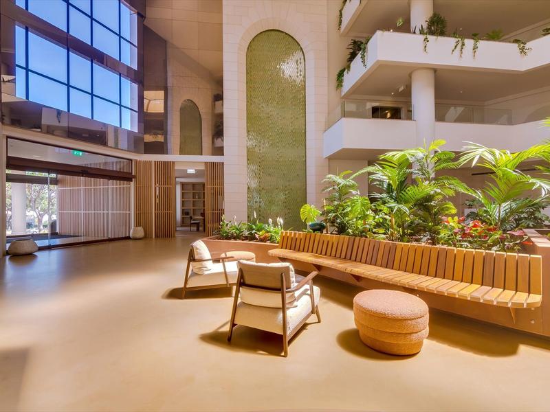 Světlá hotelová hala s pohodlným posezením a zelenými rostlinami.