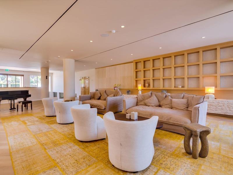 Světlý salónek s posezením, velkou knihovnou a křídlem v hotelové oblasti.