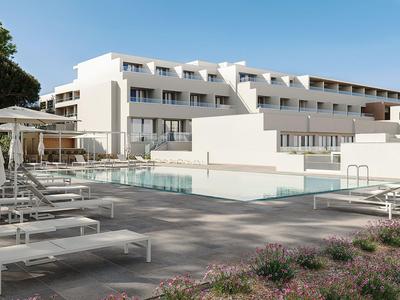 Moderner Hotelpool mit Liegestühlen und weißen Sonnenschirmen unter klarem Himmel.