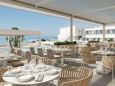 Außerrestaurant mit Holzmöbeln und Blick aufs Meer in einem Hotel.