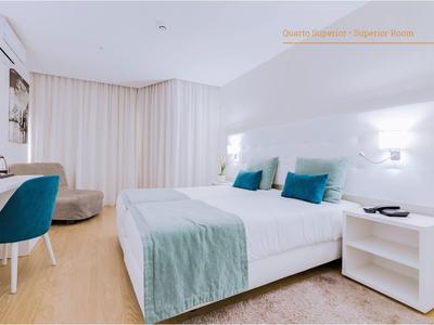 Modernes Schlafzimmer mit Doppelbett, weißen Möbeln und blaugrünen Akzenten, hellem Holzboden.