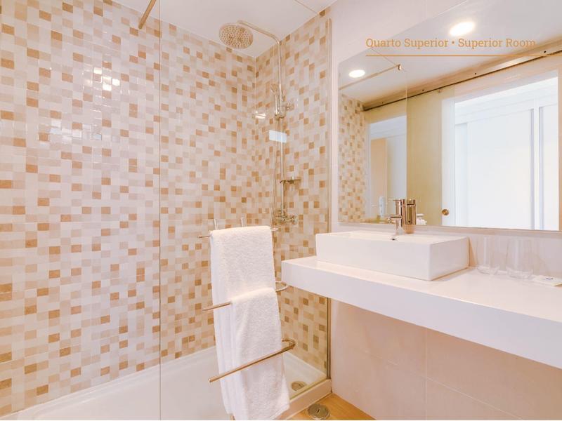 Moderne Dusche mit Glaswand, gemusterten Fliesen, weißem Handtuch und großem Spiegel im Badezimmer.