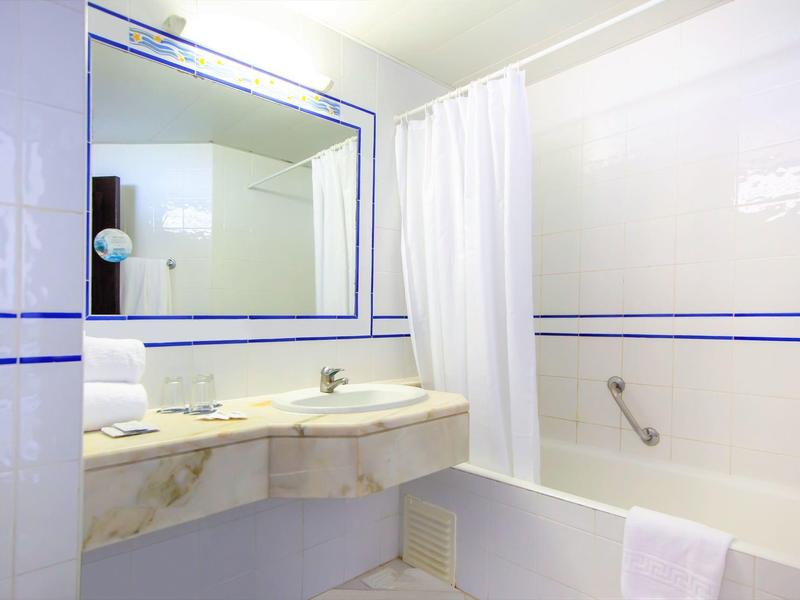 Helles Badezimmer mit weißem Marmorwaschbecken, großer Spiegel, Vorhang und Badewanne.