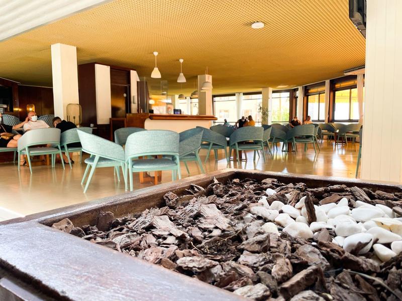 Modernes Café mit blauen Stühlen, warmem Holzdekor und einem rustikalen Kamin im Vordergrund.