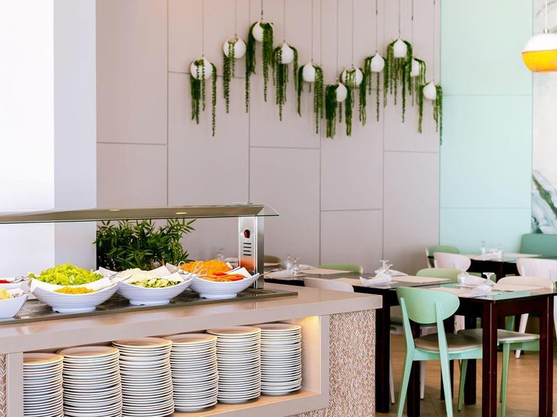 Modernes Buffet mit frischem Obst und Gemüse, helles Interieur, grüne Pflanzen, stilvolle Holzstühle.