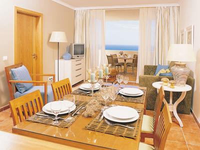 Sala da pranzo luminosa con tavolo per quattro persone, vista mare dalla finestra, arredamento accogliente.