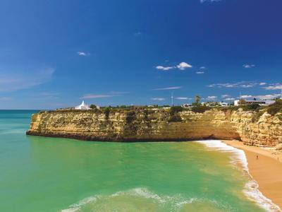 Scogliere con spiaggia di sabbia e mare turchese sotto un cielo blu terso.