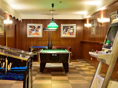 Salle de jeux confortable avec table de billard, flipper et machine d'arcade.