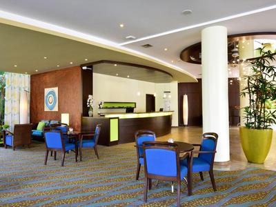 Moderna hall d'hotel con reception e sedute con sedie blu.