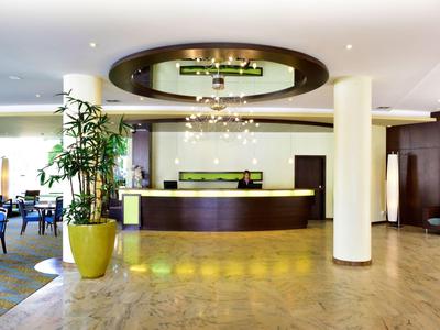 Area reception moderna di hall d'hotel con banco elegante e piante.