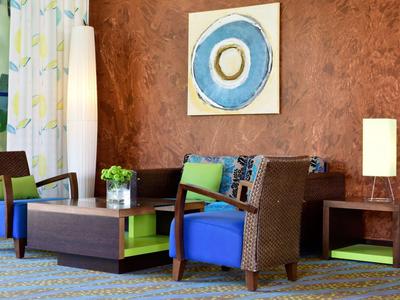 Zona lounge dell'hotel moderna con poltrone colorate e arte astratta da parete.