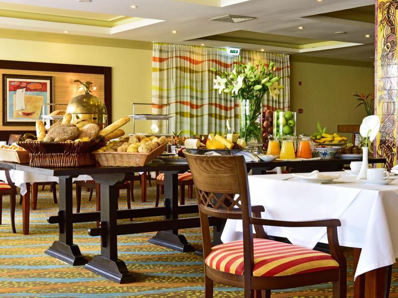 Sala da pranzo luminosa con tavoli apparecchiati e cesti di pane fresco.