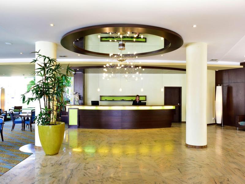 Area reception moderna di hall d'hotel con banco elegante e piante.