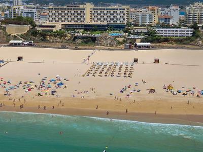 Plage avec parasols et chaises longues devant de grands hôtels et eau claire