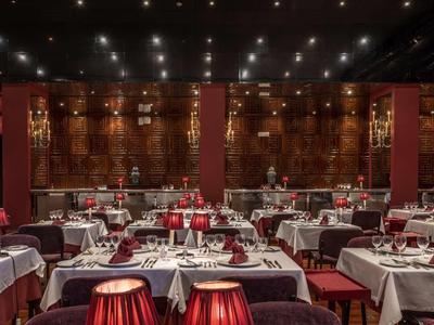Restaurant élégant avec nappes blanches, décoration rouge et éclairage tamisé.