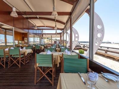 Restaurant ouvert avec mobilier vert et vue sur l'eau en bord de mer.