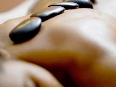 Personne allongée détendue avec des pierres chaudes sur le dos lors d'un soin bien-être.