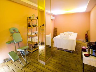 Salle de bien-être confortable avec fauteuil de massage, table de soin et sol en bois chaleureux.