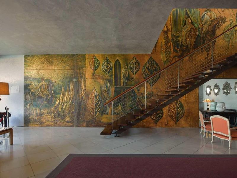 Grande pièce avec mur peint, escalier en bois et coin salon moderne.