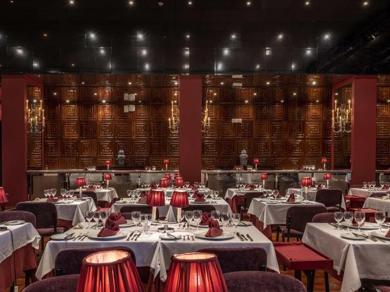 Restaurant élégant avec nappes blanches, décoration rouge et éclairage tamisé.