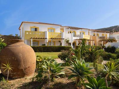 Modernes Hotelgebäude mit weißen Wänden und grünen Pflanzen im Vordergrund bei blauem Himmel.