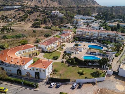 Luftaufnahme eines Hotels mit mehreren Gebäuden und zwei Schwimmbädern in einer bergigen Landschaft.